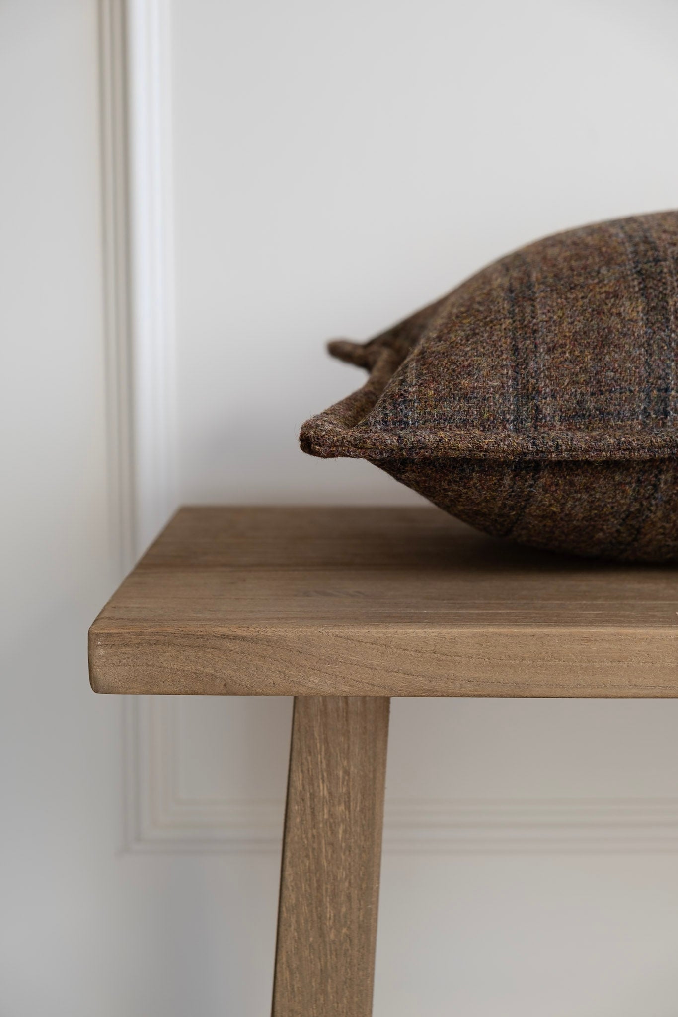 Brown Check Tweed Cushion side view on a wooden bench. Woven, designed and made in Ireland. Irish Tweed. Handmade