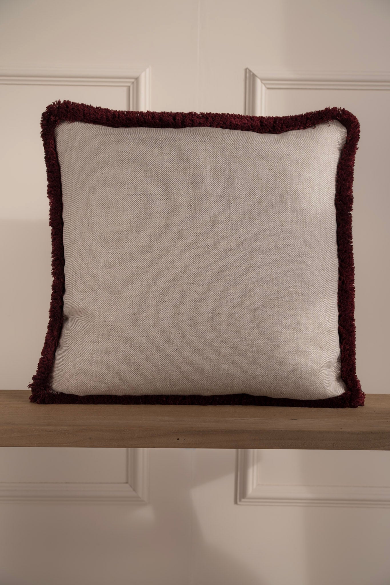 Herringbone Linen cushion on a bench with burgundy fringe detail. 100% Irish Linen, Made In Ireland