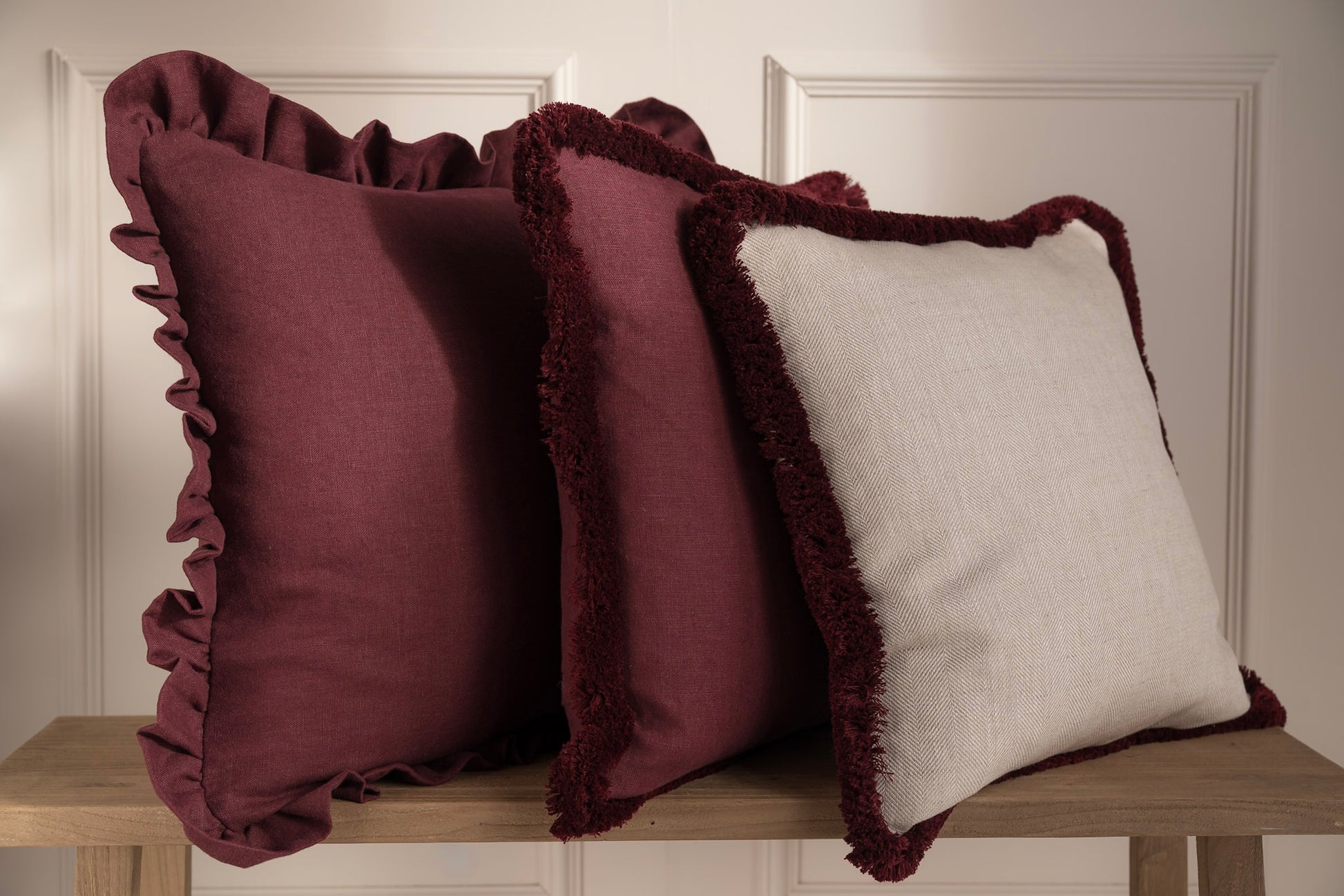 A stack of burgundy cushions on a bench. 100% Irish Linen. Made in Ireland