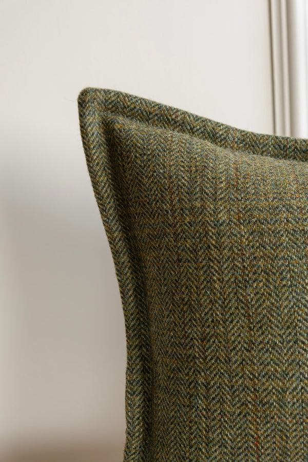 Green Tweed Cushion. Irish Tweed cushion. A close-up of a green tweed cushion with a herringbone and check pattern design, featuring a stitched border. Available in a Lumbar Bolter, or Square cushions. Woven and Made in Ireland.