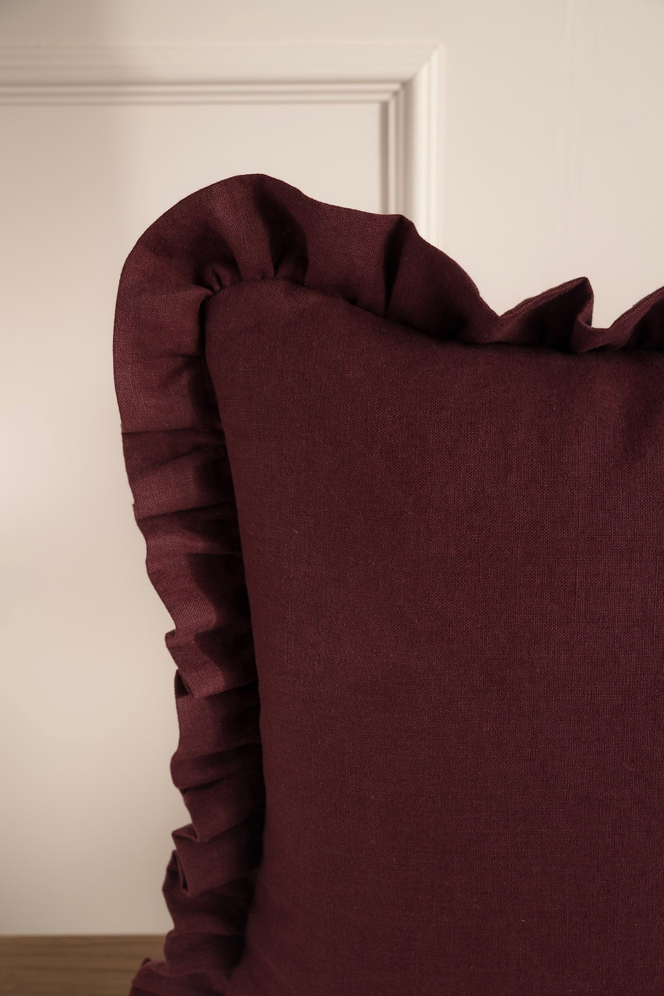 Close-up of a burgundy cushion with ruffled edge. 100% Irish Linen Made in Ireland
