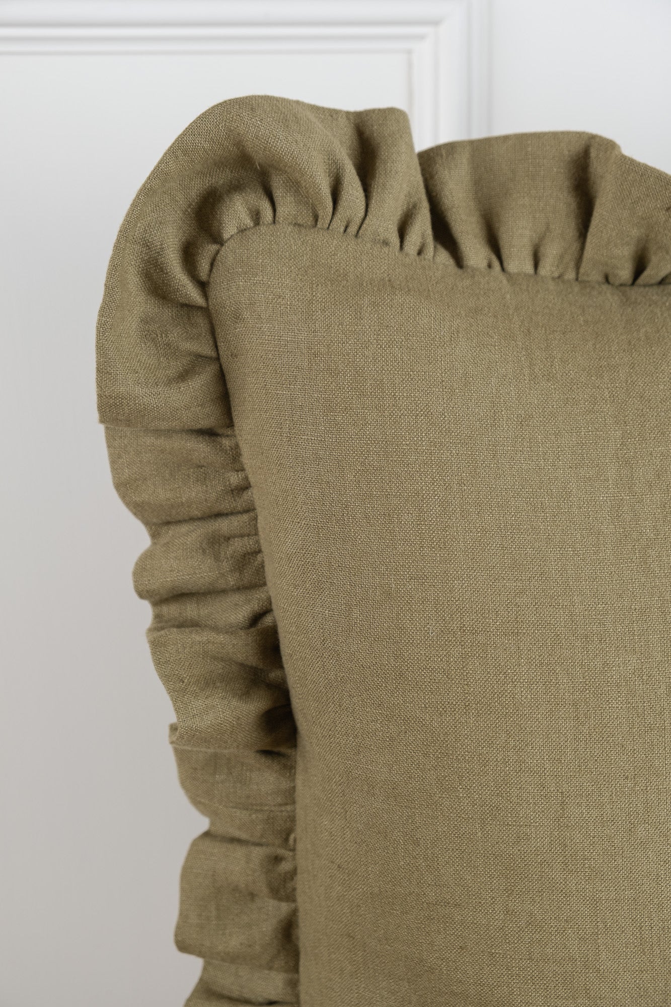 A Olive linen cushion featuring a frilled gathered edging. 100% Irish Linen, Woven and Made in Ireland. This linen has a beautiful laundered finish which leaves a beautiful textured natural finish to the cushion