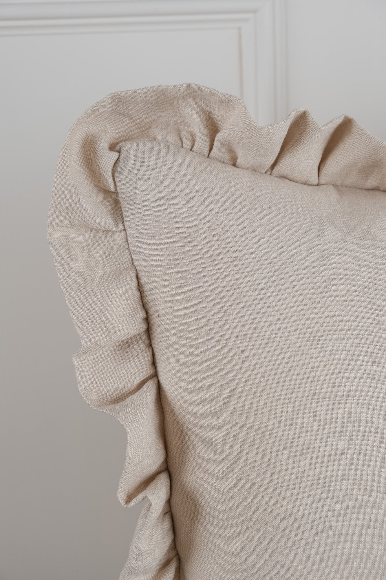 A light soft pink beige linen cushion featuring a frilled edging. 100% Irish Linen, Made in Ireland. Frilled gathered edging. Plump cushion