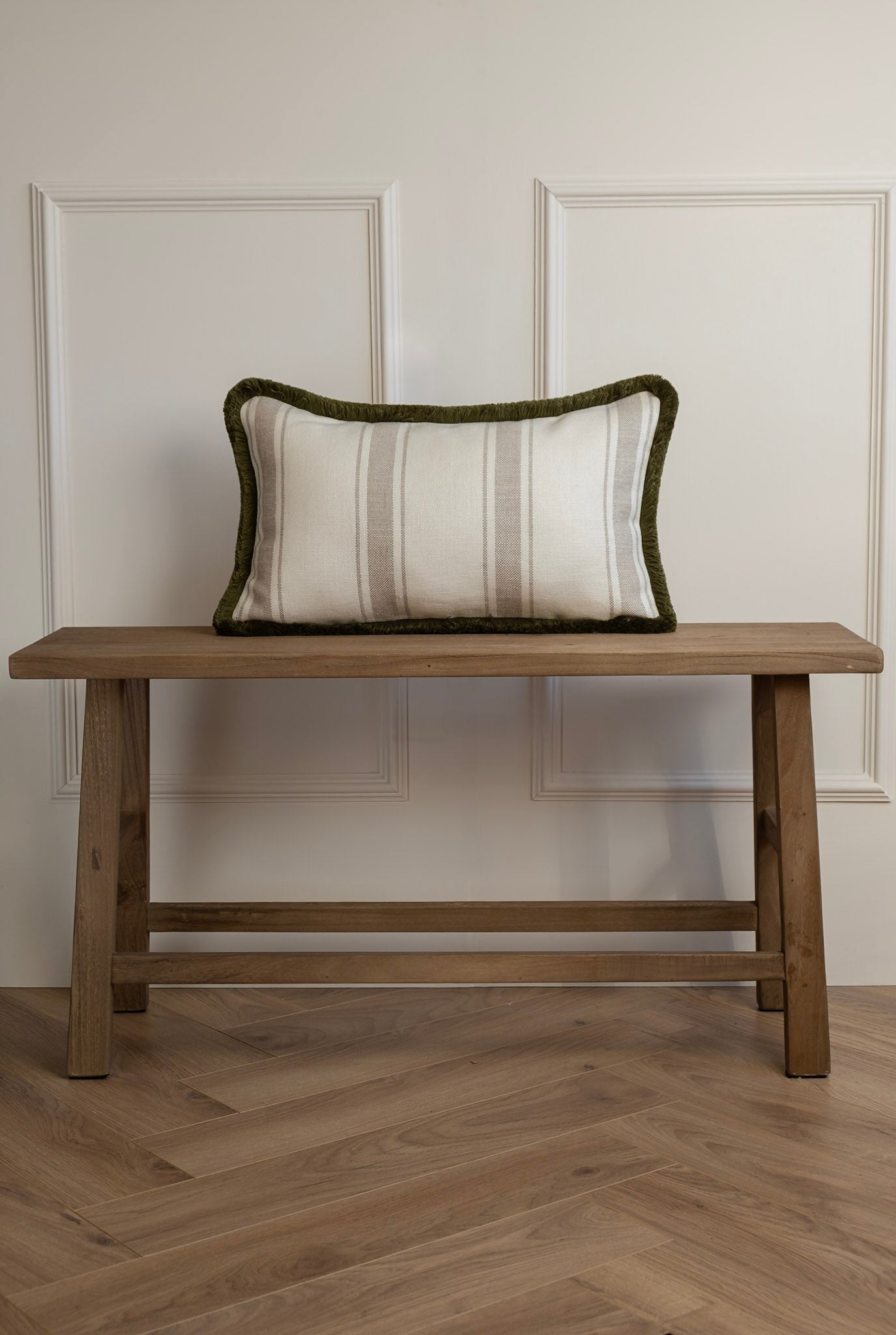 A neutral stripe lumbar cushion with olive fringe detail