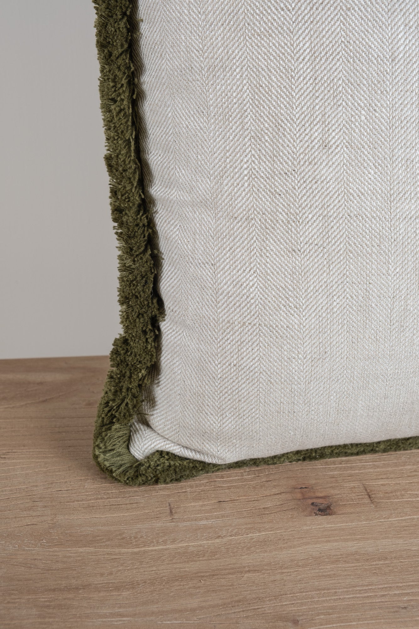 Close up of a neutral coloured herringbone cushion with deep olive fringe detail. 100% Irish Linen